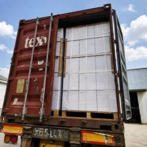 A shipping container packed with tall cardboard boxes stabilized using composite cord strapping on wooden pallets